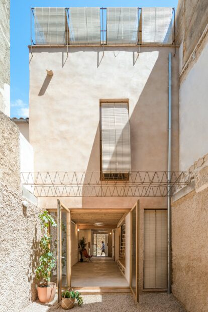 Fachada posterior revestida de mortero de cal con color arena que da al patio interior.