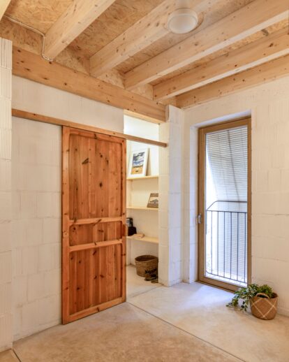 Espacio interior con puertas de madera recuperadas y luz natural en una de las habitaciones de la vivienda.